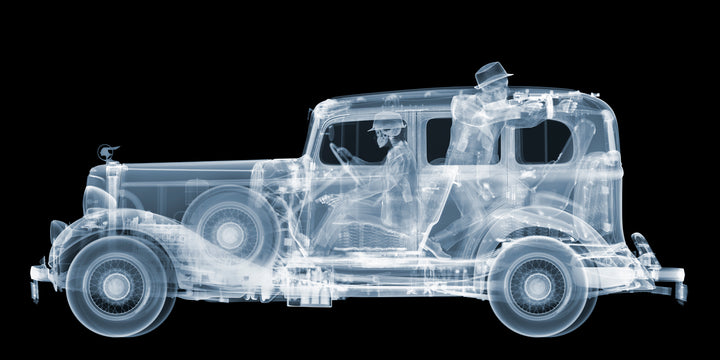 Framed Chromaluxe black and white x-ray photograph by Nick Veasey of a skeleton 1930s gangsters in a pontiac getaway car, pointing a vintage machine gun