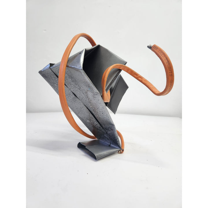 folded abstract piece of metal origami style with wire cable throughout orange and grey