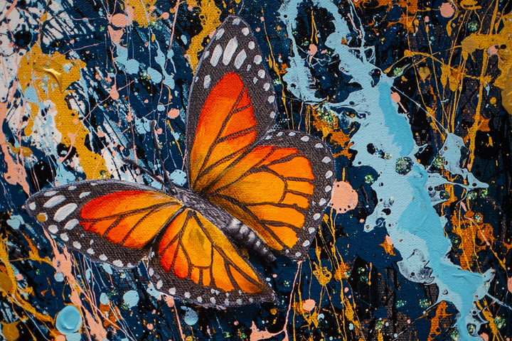 black and white woman flipping hair back with gold blue and black splatter paint, orange monarch butterflies in hair on white background