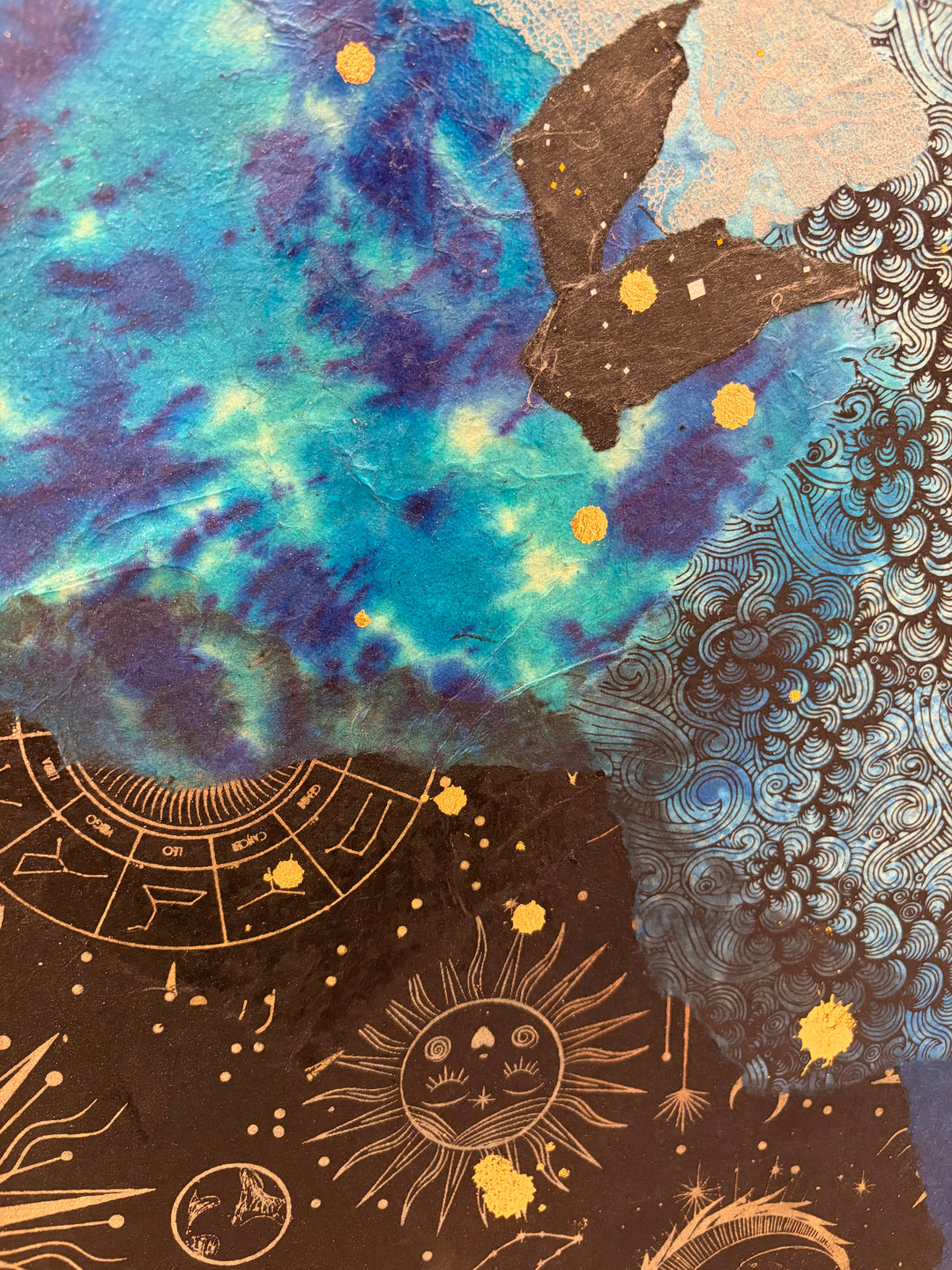 Christopher Peter, Born to Be Blue, acrylic, oil, handmade papers and gold leaf on canvas, 48 x 40 inches. Detail of the chest, showing turquoise and violet mottled paper, a black paper fragment, blue paper printed with black swirls, and black paper printed with a gold zodiac wheel, a sun with a face, and stars, accented with gold leaf dots.