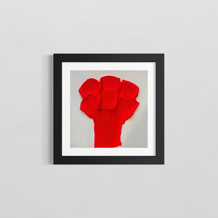 Lee in Cerulean, Botanic Rouge, joint compound and acrylic, 14 x 14 inches, shown in a black frame with a white mat on a light grey wall. A bright red flower-like form of layered petal shapes on a vertically ribbed stem, on a white background.