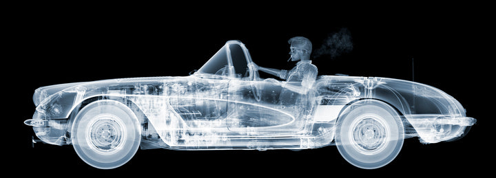 Framed Chromaluxe black and white x-ray photograph by Nick Veasey of a skelton man driving a vintage corvette cruiser while spoking a cigarette