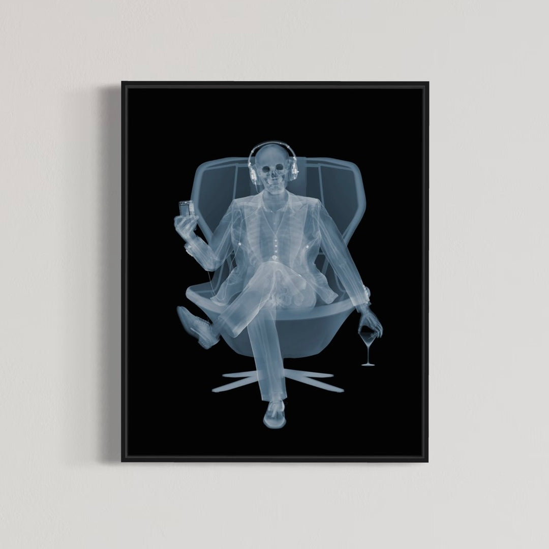 Framed Chromaluxe x-ray photograph by Nick Veasey of a skeleton listening to music with headphones in a swivel chair with a martini