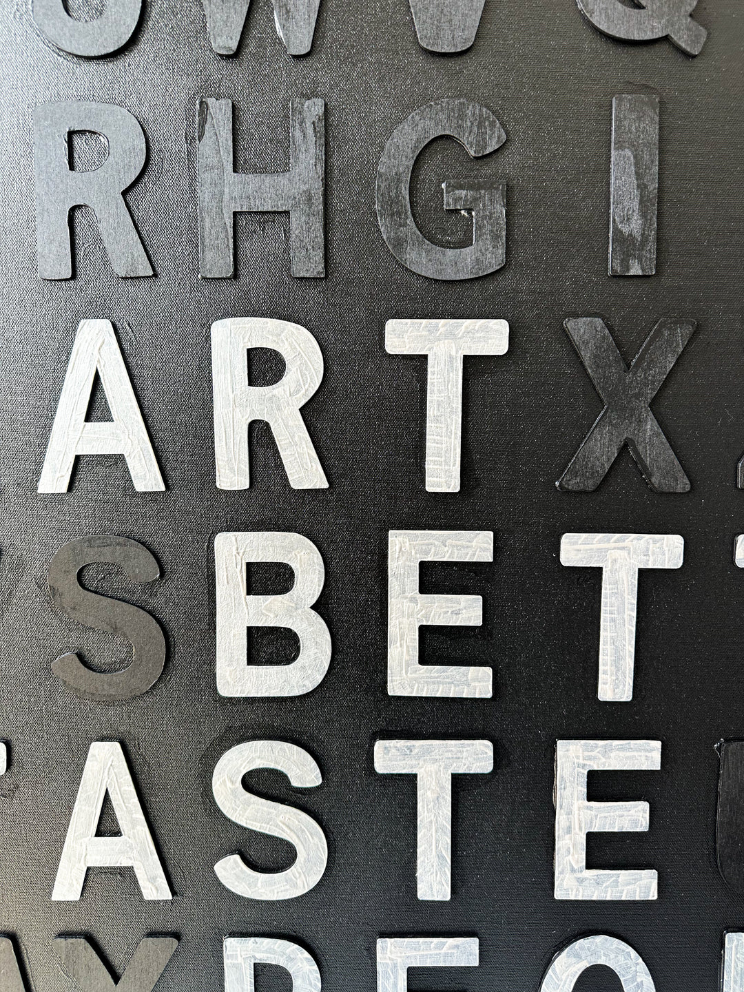 Steffanie Gerkin’s Have Good Taste Black 3D is a contemporary mixed-media typography artwork made with raised wood and acrylic letters on canvas, featuring a black monochrome alphabet grid with contrasting white letters that spell phrases including “Have Good Taste,” “Art,” “Better Taste,” and “People.”