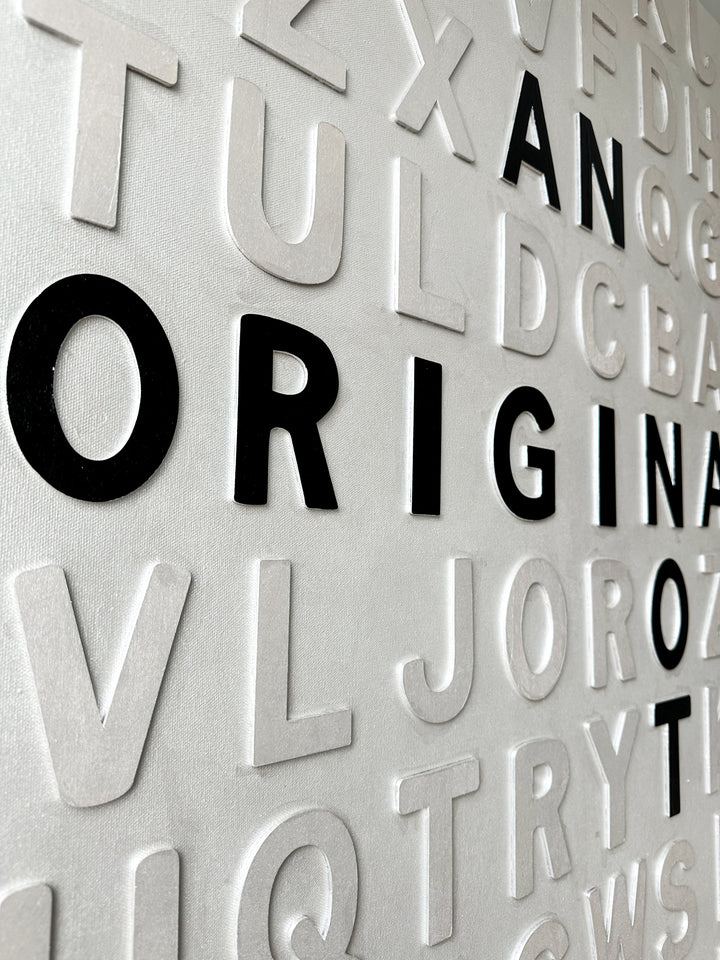 Contemporary 3D text artwork by Chicago artist Steffanie Gerkin titled I’m an Original 3D, featuring raised black and white wood letters arranged in a structured alphabet grid on a white canvas. The monochrome typographic composition spells the phrase “I’m an Original, Not a Print,” creating a bold conceptual wall art piece with graphic text-based design, pop art influence, and contemporary mixed-media style.