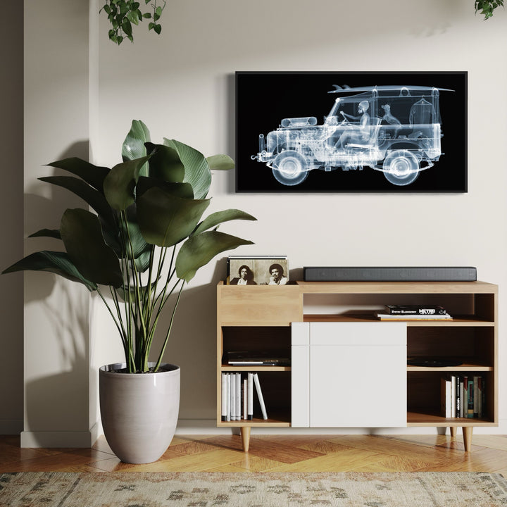Framed Chromaluxe black and white x-ray photograph by Nick Veasey of a skeleton man driving a land rover with a surf board on the roof and a dog and surf suit in the back of the car. 