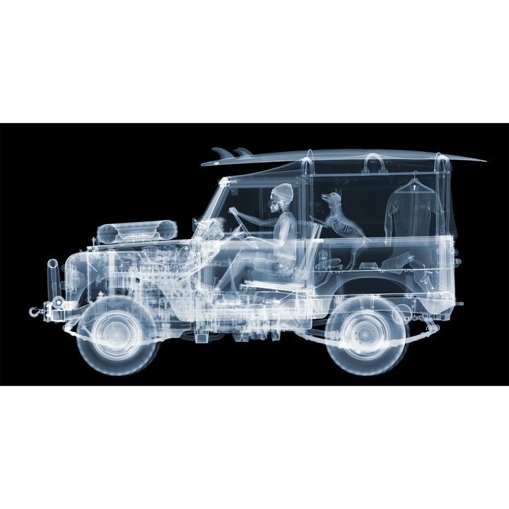 Framed Chromaluxe black and white x-ray photograph by Nick Veasey of a skeleton man driving a land rover with a surf board on the roof and a dog and surf suit in the back of the car. 