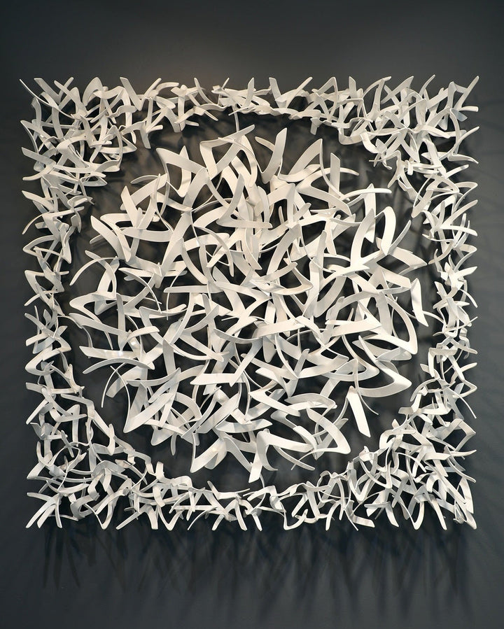 Matt Devine, Avian, powder-coated aluminum, made to order from 11 to 84 inches. Square wall sculpture of many small, curved white aluminum pieces shaped like bird wings, forming a dense center surrounded by a square border, on a dark grey wall.