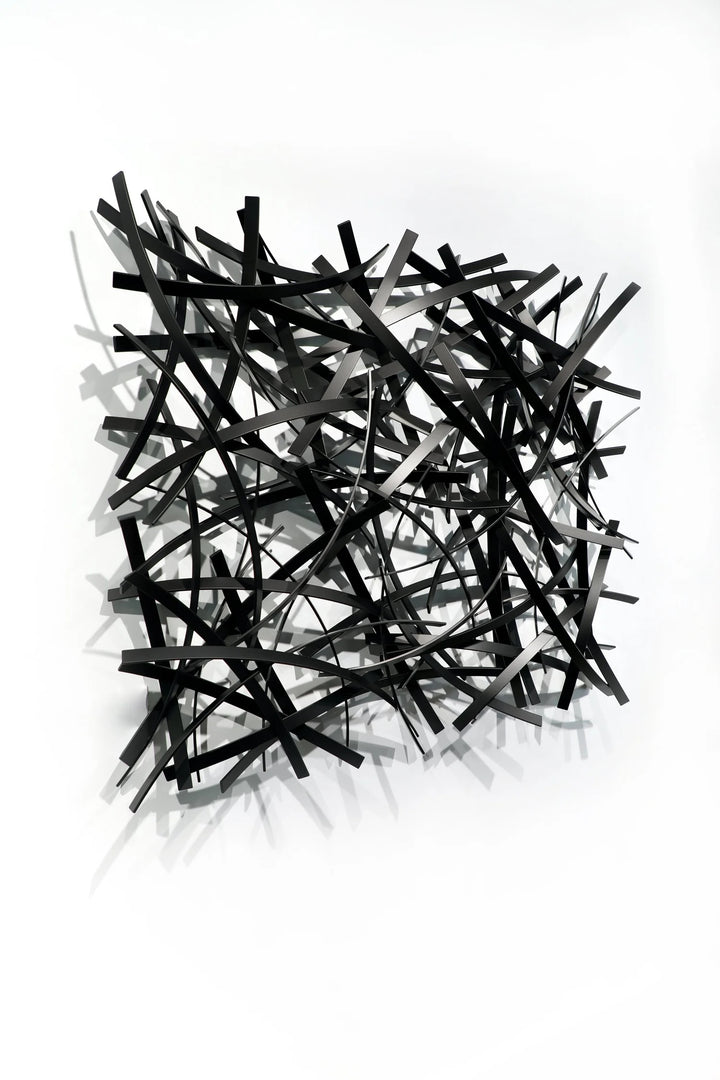 Matt Devine, Thin Bands, powder-coated aluminum, made to order from 11 to 84 inches. Square wall sculpture of thin, curved black and grey aluminum strips layered in a dense crisscross pattern on a white wall.