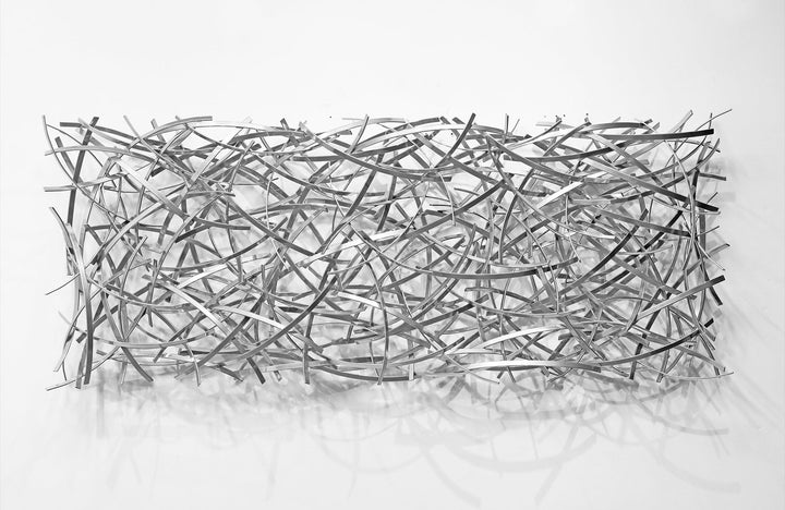 Matt Devine, Thin Bands, powder-coated aluminum, made to order from 11 to 84 inches. Long horizontal rectangular wall sculpture of thin silver aluminum strips layered in a dense crisscross pattern on a white wall.