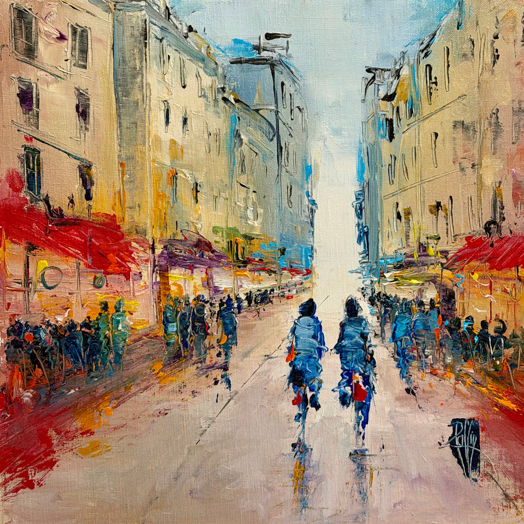 Christian Raffin, Paris D'un Jour, oil on canvas, 14 x 14 inches. A street between tall cream buildings with red café awnings, crowds of small figures on both sides, and two cyclists in blue riding down the center.