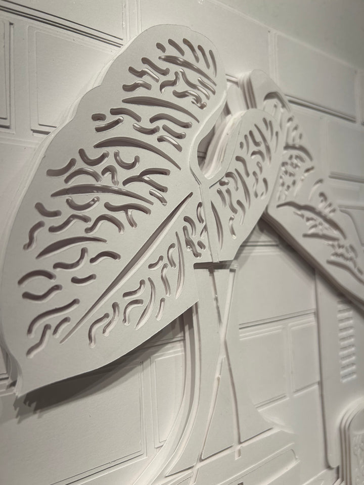 14"x14" layered white paper forming a a vase with leaves on a wall. 