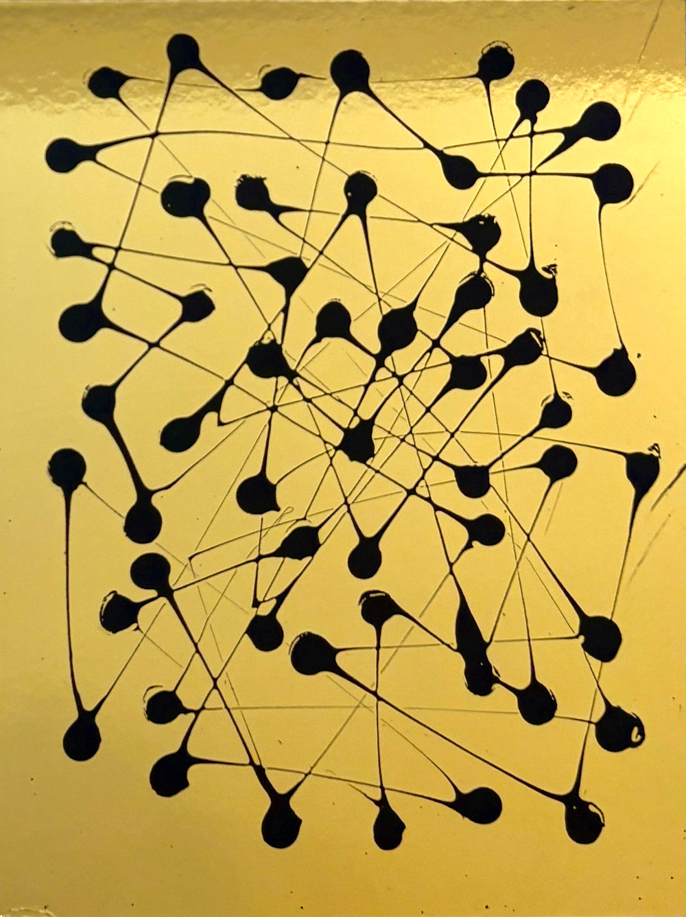 abstract expressionistic pointillism of black paint dots on smooth shiny reflective gold surface by m clark