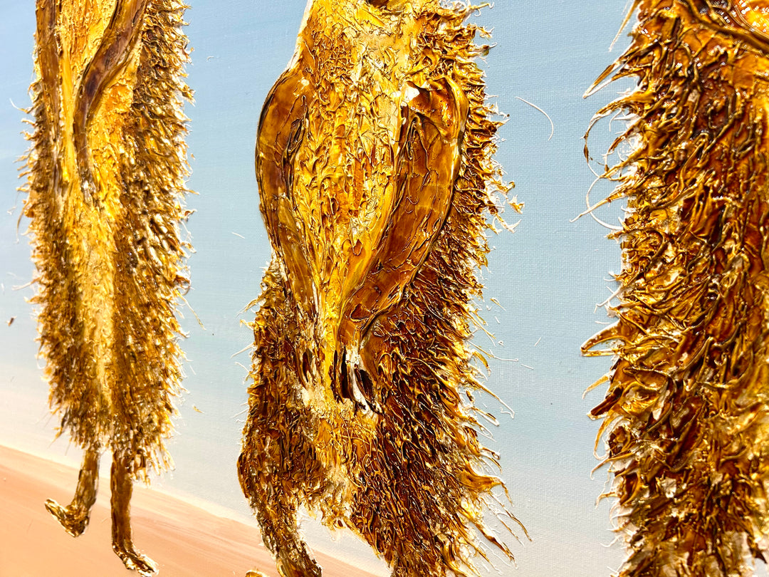 30” x 30” painting by French artist Moogly of three goldish-brown merecats. The two merecats on the sides look left and right while the smallest one in the middle looks straightforward with a light blue background. The merecats are made out of resin, giving them a textured and shiny finish. Their eyes are made out of washers that the artist has adhered to the canvas.